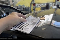 a person is holding a piece of paper on a car